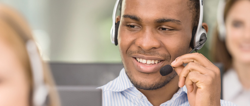 A smiling man, wearing a headset, smiles.